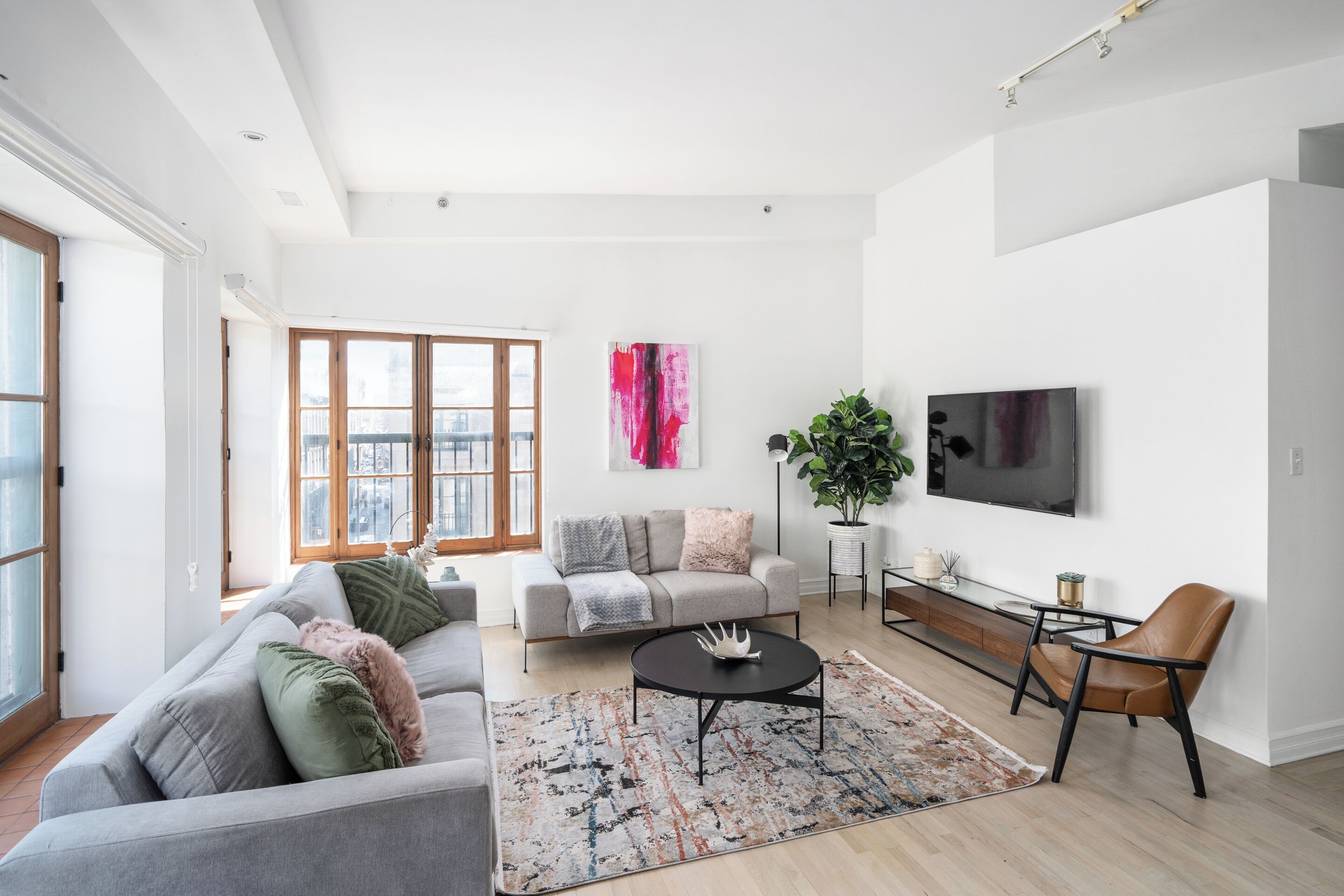 Ein modernes Wohnzimmer mit einem grauen Sofa, einem Couchtisch und einem an der Wand befestigten Fernseher.