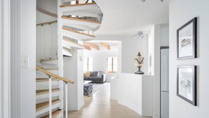 A modern interior with a spiral staircase, a living room with a sofa and a coffee table, and framed artwork on the walls. - Le Nomade MTL (Montreal)