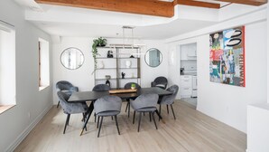 A modern dining area with a wooden ceiling, a central table with chairs, and a wall-mounted mirror. - Le Nomade MTL (Montreal)