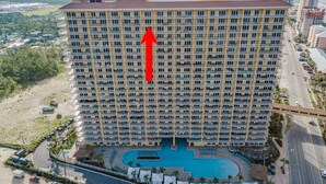 Un hotel de gran altura con varios balcones, una piscina y vistas del entorno.