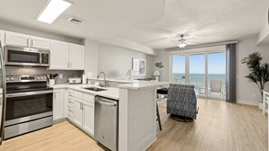 Una cocina moderna con armarios blancos, electrodomésticos de acero inoxidable y vistas al balcón.