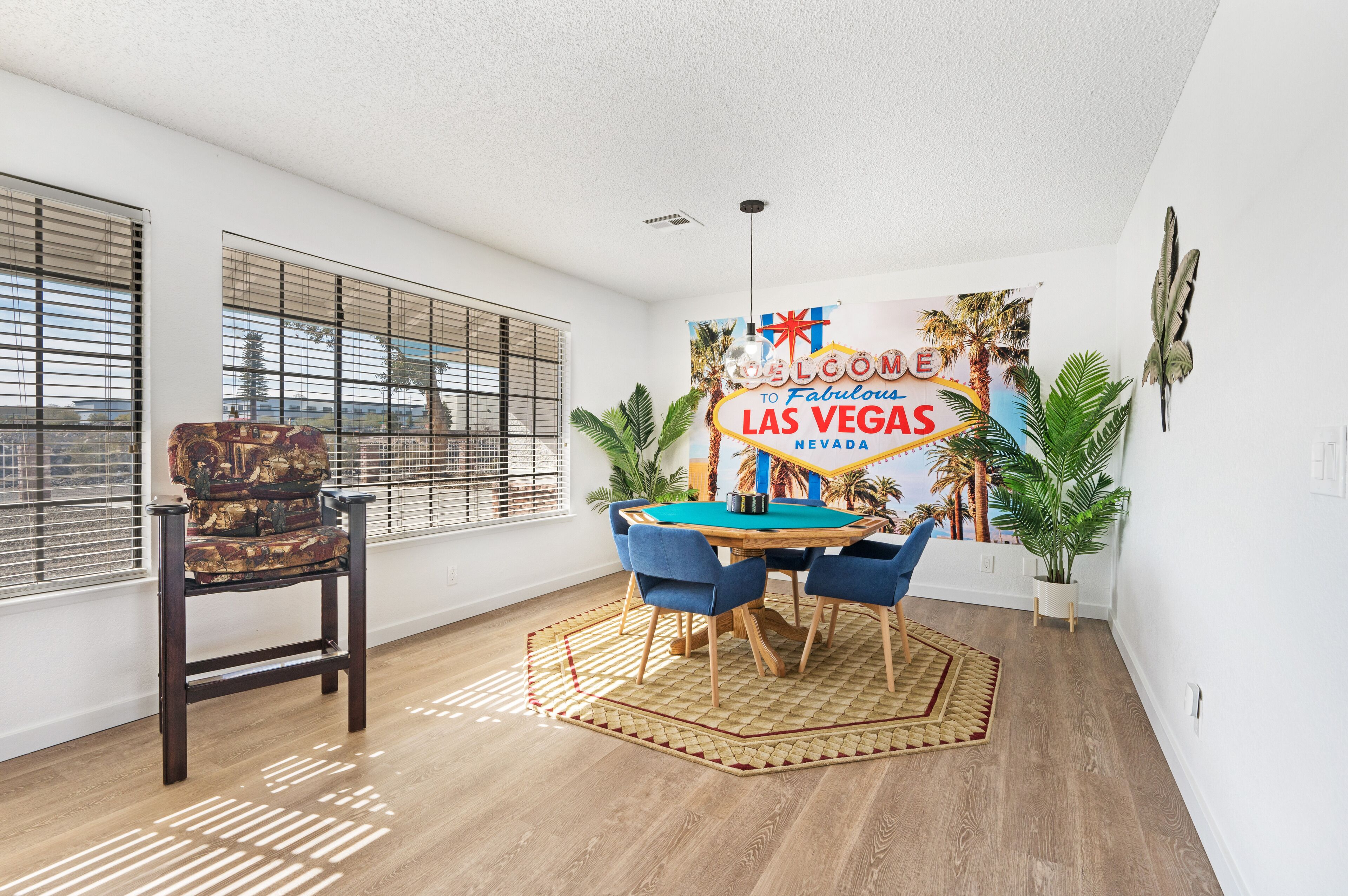 A room with a pool table, a chair, a neon sign, and a view of the city.