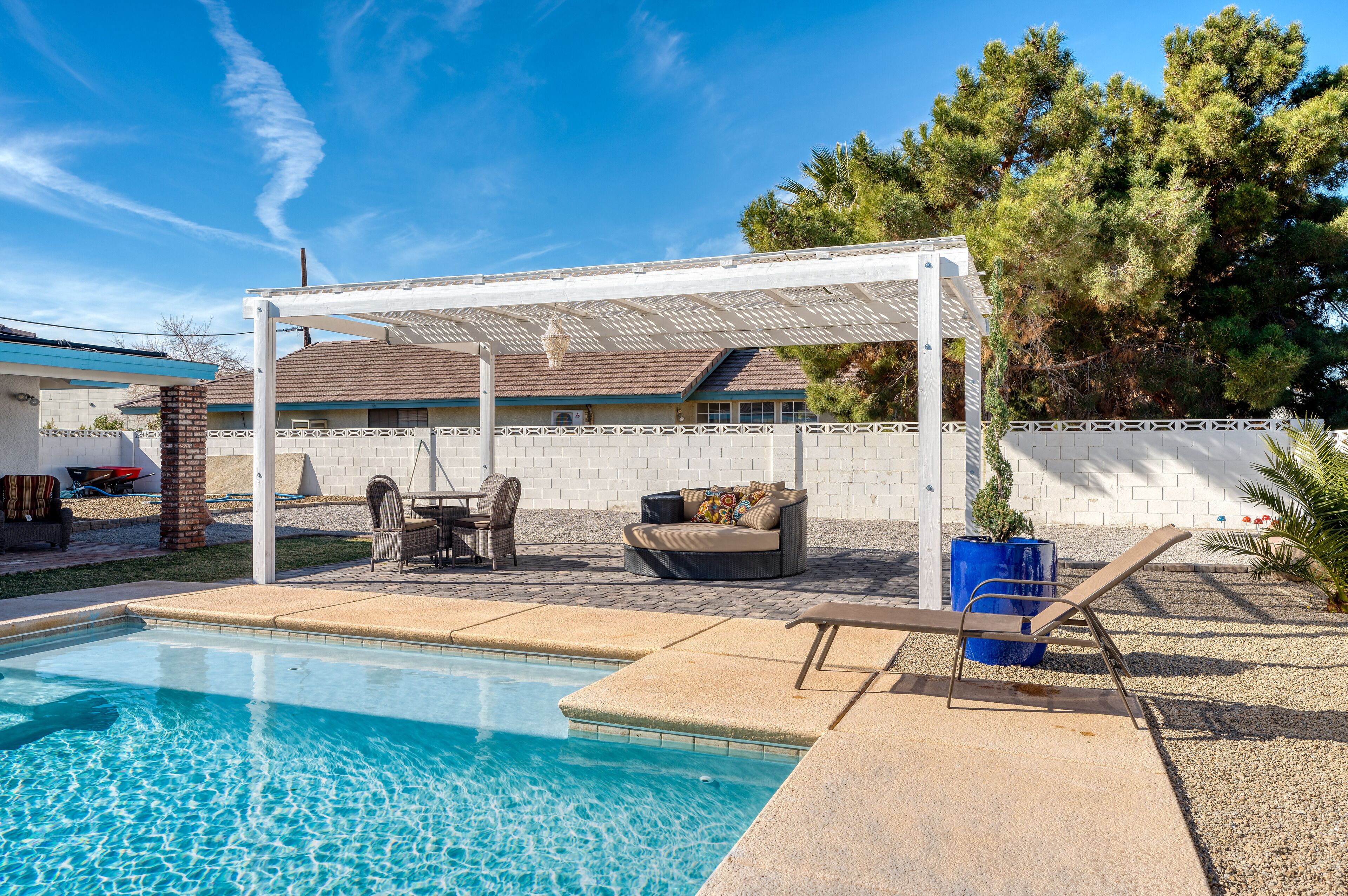 A backyard with a swimming pool, patio furniture, and a pergola.