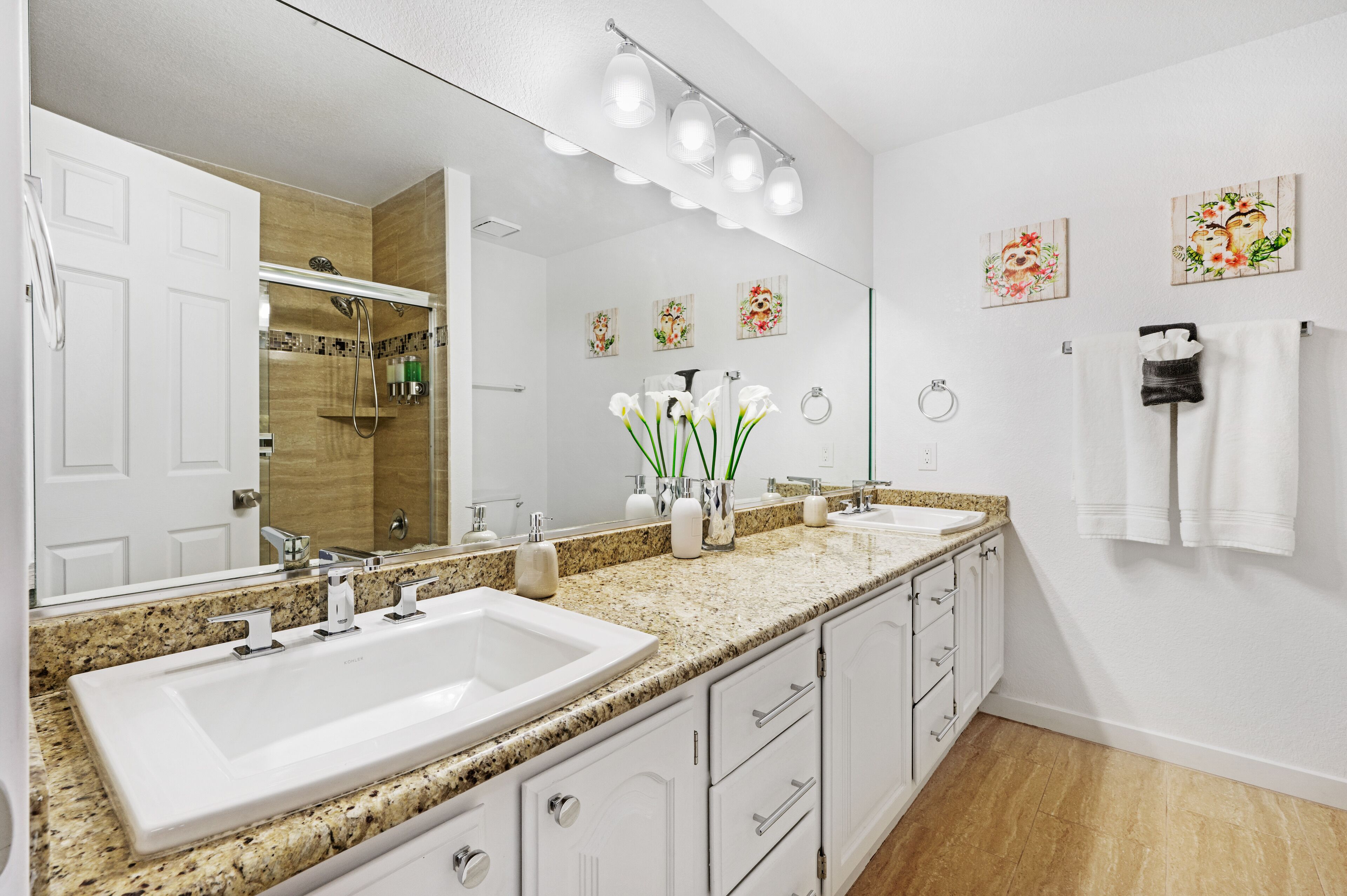 Een moderne badkamer met twee wastafels, een grote spiegel en een douche.
