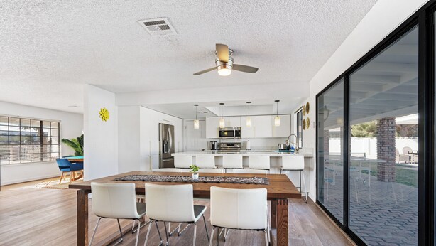 A modern kitchen with white cabinets, a wooden dining table, and a ceiling fan. - Las Vegas Dream House with Backyard Oasis (Henderson)