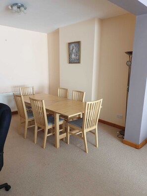 A dining area with a wooden table and six chairs, a ceiling light fixture, and a framed picture on the wall. - Mountsorrel House (Loughborough)