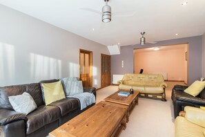 A modern living room with a brown leather sofa, a wooden coffee table, and a yellow armchair. - Mountsorrel House (Loughborough)