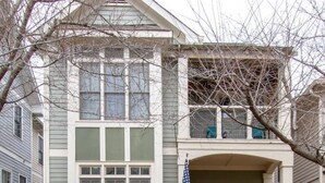 Ein zweistöckiges Haus mit gelber Haustür, einer kleinen Veranda und einer amerikanischen Flagge.