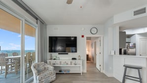 A living room with a large TV, a sofa, and a view of the ocean. - Fall Dates Available! Book Now! Great Location! (Panama City Beach)