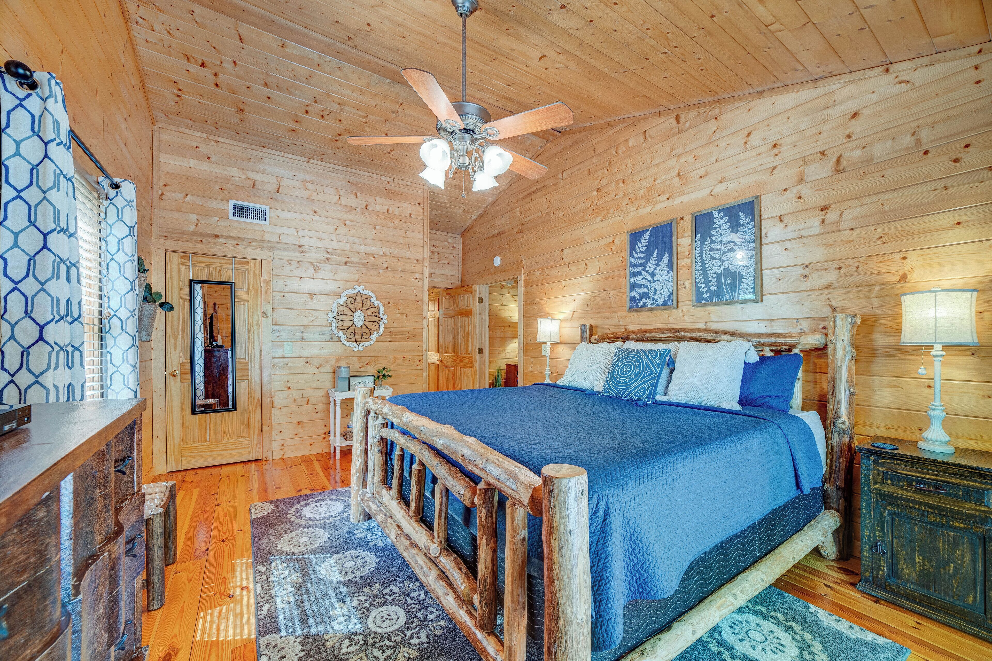 Ein Schlafzimmer in einer Holzhütte mit einem Bett, einem Deckenventilator und einem rustikalen Holz-Kopfteil.