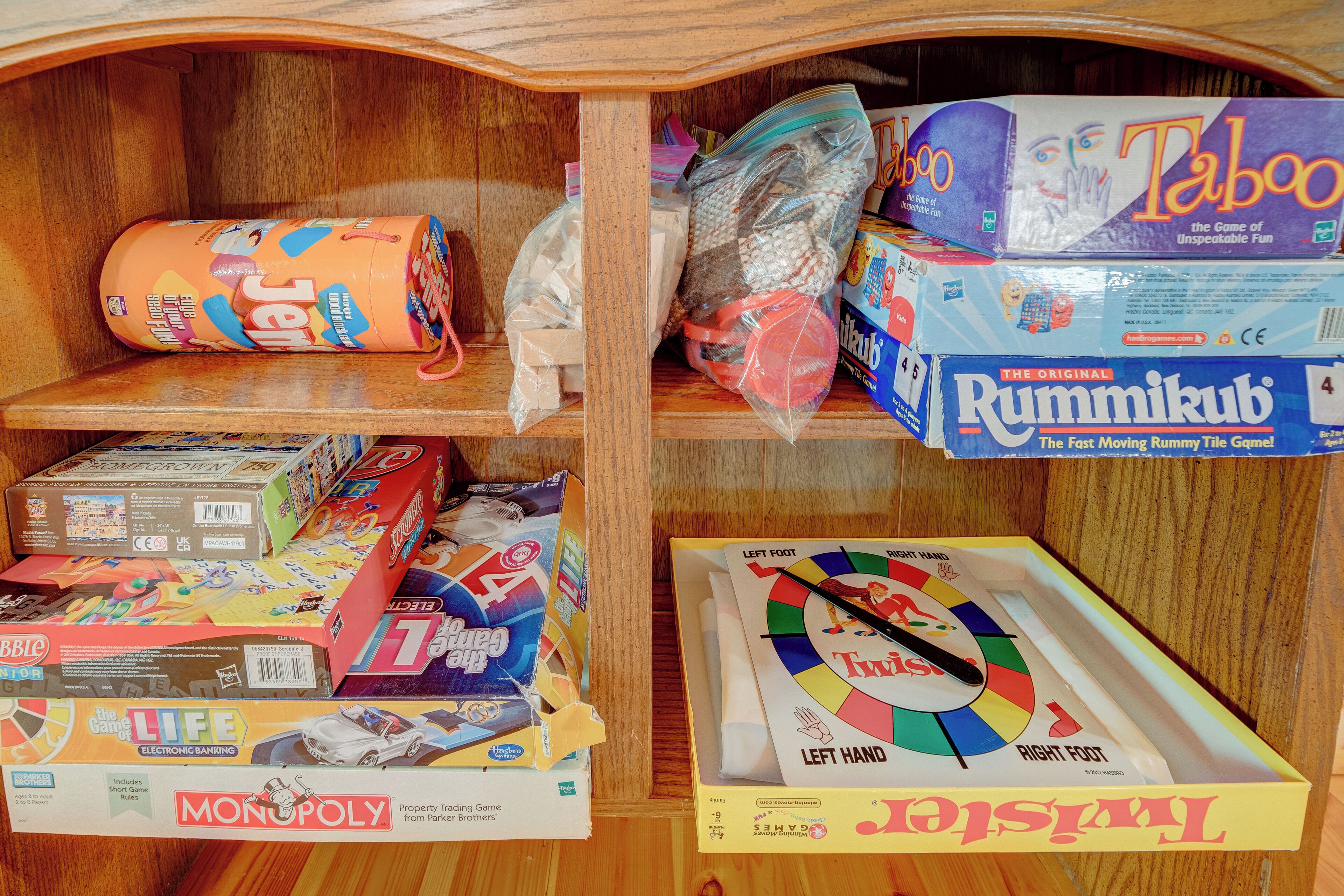 A wooden shelf with various board games, including Monopoly and Scrabble.