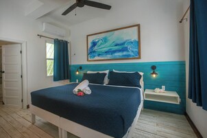 Un dormitorio con cama, un cuadro, una mesita de noche y una ventana con cortinas.