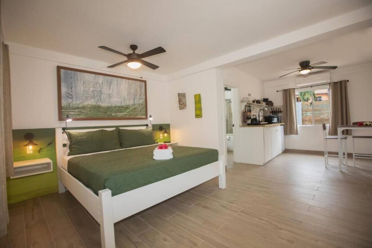 Un dormitorio con cama, lámparas de noche, ventilador de techo y un cuadro en la pared.