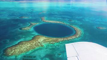 An aerial view of a turquoise lagoon with coral formations, surrounded by clear blue water.