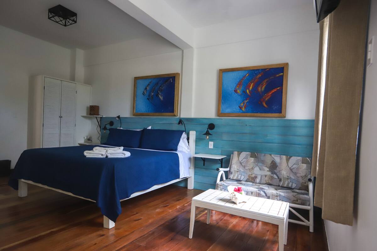 Un dormitorio con una cama, una mesita de noche, una silla y dos cuadros en la pared.
