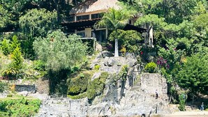 A coastal house with a stone staircase leading to a balcony, surrounded by lush greenery and overlooking a body of water. - Lakeview on the Rocks (San Antonio Palopó)