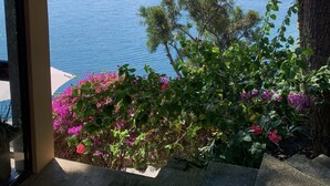 A view from a covered outdoor area with a thatched roof, overlooking a body of water and a mountainous landscape. - Lakeview on the Rocks (San Antonio Palopó)