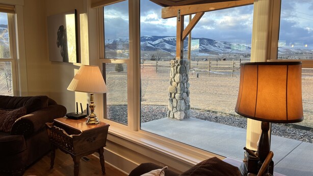 A cozy living room with a large window offering a view of a snowy landscape. - Modern Dog Friendly Paradise Valley Home near Yellowstone NP & Chico Hot Springs (Pray)