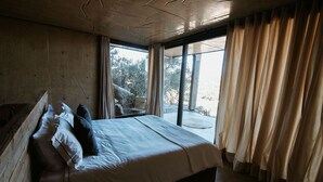 A bedroom with a large bed, a wooden bench, and a view of the outdoors through a window. - Vineyard Desert House -CuatroCuatros-CasaUno (Ensenada)