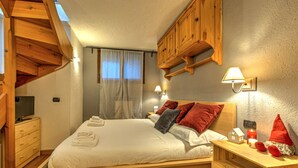 Ein Schlafzimmer mit einem hölzernen Bett, einem Nachttisch, einem Fernseher und einer Holzbalkendecke.