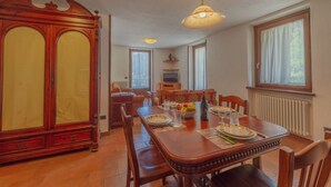 Ein Essbereich mit einem Holztisch, gedeckt für vier Personen, einem großen Holzschrank und einem Fernseher im Hintergrund.