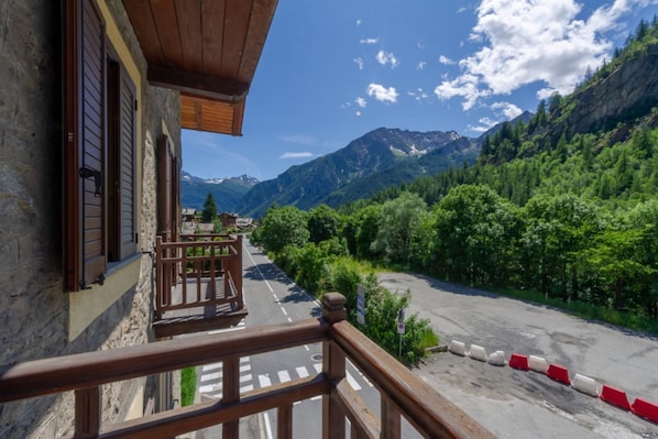 A balcony with a view of a mountain road and forest.