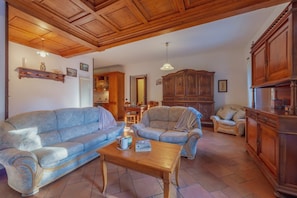 Un salon comprenant un canapé, un fauteuil, une table basse en bois et un coin repas avec des chaises et une table.