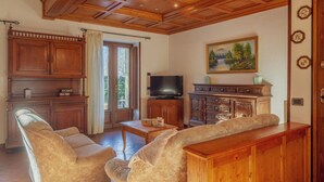 Ein Wohnzimmer mit Holzboden, einem Fernseher, einer Couch und einem Schrank.