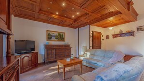 Ein Wohnzimmer mit Holzboden, einem Fernseher, einem Sofa, einer Kommode und einem Gemälde an der Wand.