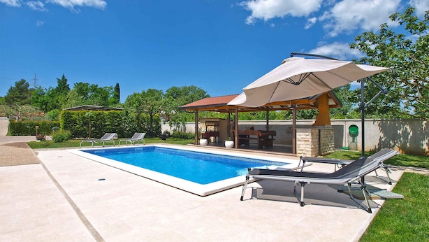 A swimming pool with lounge chairs and a covered seating area. - Villa with pool for 6 people (Pula)