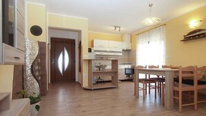 A modern kitchen with wooden cabinets, a dining area with a wooden table and chairs, and a hallway with a decorative door. - Villa with pool for 6 people (Pula)