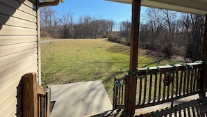 A covered porch with a view of a grassy yard and trees. - Mountain Hideaway  (Ronceverte)