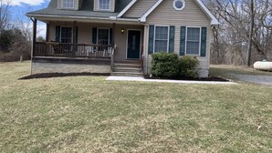 A two-story house with a front porch, a small front yard, and a large window on the second floor. - Mountain Hideaway  (Ronceverte)