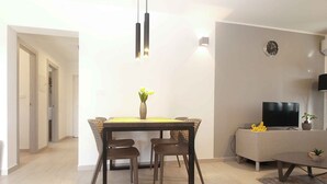 A modern living room with a dining area, a flat-screen TV, and a minimalist design. - Holiday home with air conditioning (Fažana)