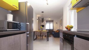 A modern kitchen with a microwave, refrigerator, and stove. There is a dining area with a table and chairs. - Holiday home with air conditioning (Fažana)