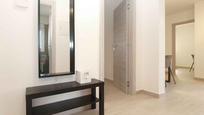 A hallway with a dark wooden bench, a large mirror, and a door leading to another room. - Holiday home with air conditioning (Fažana)