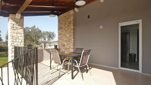 An outdoor patio with a table and chairs, stone pillars, a wooden ceiling, and a door leading to an interior space. - Holiday home with air conditioning (Fažana)