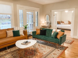 A living room with a green sofa, a brown sofa, a coffee table, and a rug.