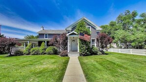 A two-story house with a front porch, a small American flag, and a well-maintained lawn. - Captain Cook, Hot Tub, Sleeps 9 (Lake Geneva)