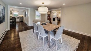 A dining area with a wooden table, six chairs, a chandelier, and a rug. - Captain Cook, Hot Tub, Sleeps 9 (Lake Geneva)