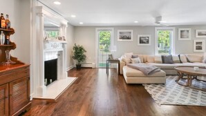 A living room with a fireplace, a sofa, a coffee table, and a wooden cabinet. - Captain Cook, Hot Tub, Sleeps 9 (Lake Geneva)
