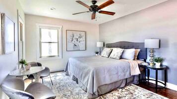 A bedroom with a bed, bedside tables, a ceiling fan, a window, and a chair.