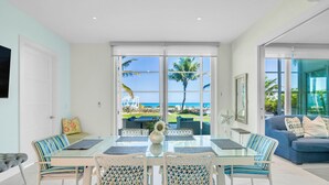 Un coin repas avec une table et des chaises en verre, un canapé et une vue sur l’océan.