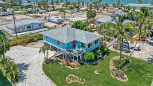 A two-story building with a blue exterior and a grey roof, surrounded by a well-maintained lawn and palm trees. - 120 Bay Mar Dr (Fort Myers Beach)