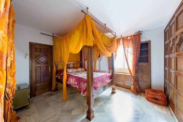 A four-poster bed with a canopy, a wooden wardrobe, and a door with a decorative pattern.