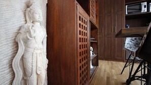 A room with a wooden cabinet, a white statue, and a chair. - Terraza Tailandia by Rentalsevilla (Sevilla)