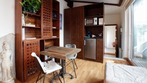 A compact kitchen with wooden cabinetry, a dining table with chairs, and a refrigerator. - Terraza Tailandia by Rentalsevilla (Sevilla)
