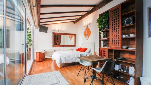 A modern bedroom with a large bed, a wooden table, and a built-in bookshelf. - Terraza Tailandia by Rentalsevilla (Sevilla)