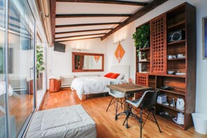A modern bedroom with a large bed, a wooden table, and a built-in bookshelf. - Terraza Tailandia by Rentalsevilla (Sevilla)