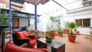 An outdoor patio with wicker furniture, potted plants, and a white umbrella. - Terraza Tailandia by Rentalsevilla (Sevilla)